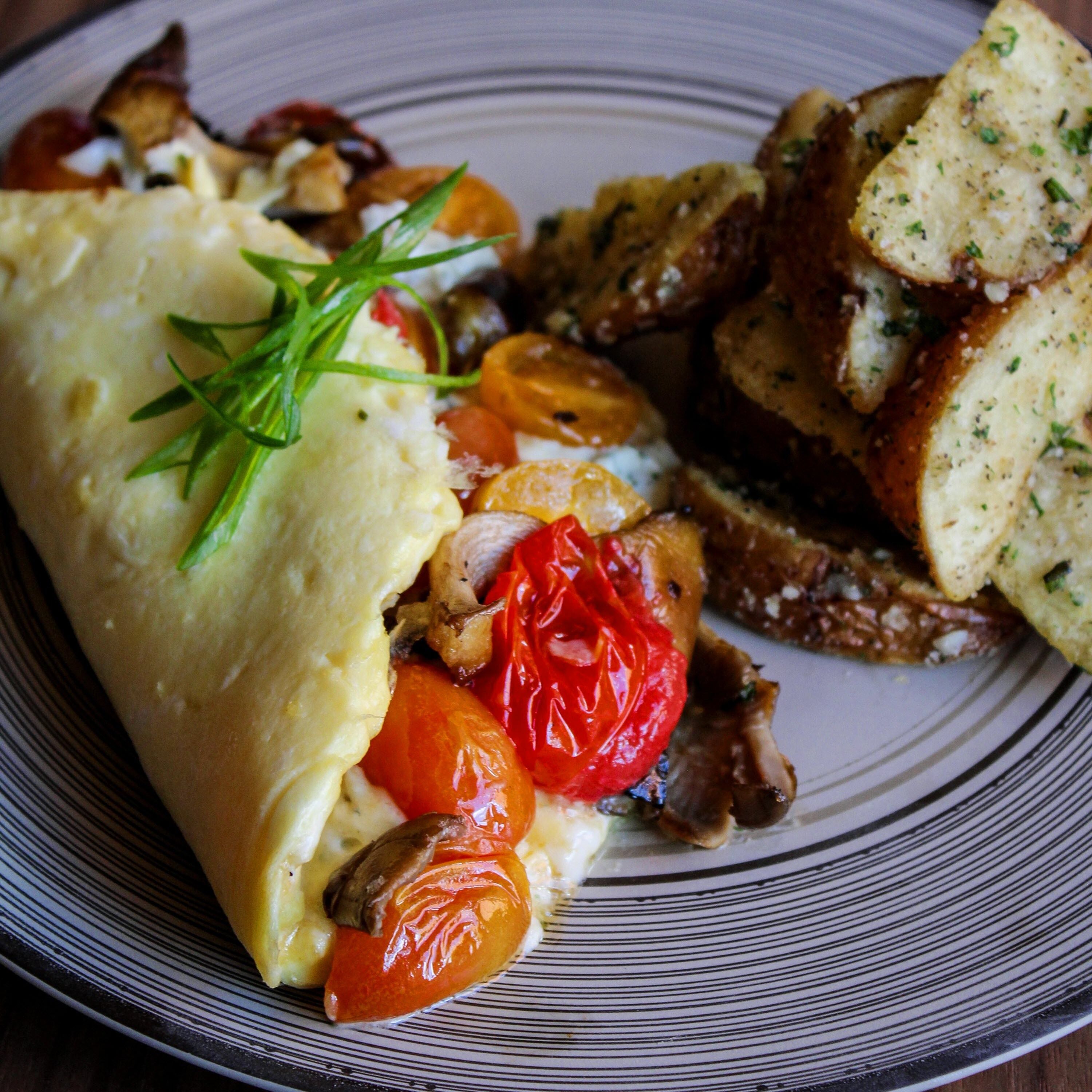 Un plato con una tortilla, tomates asados, champiñones y pan con ajo.