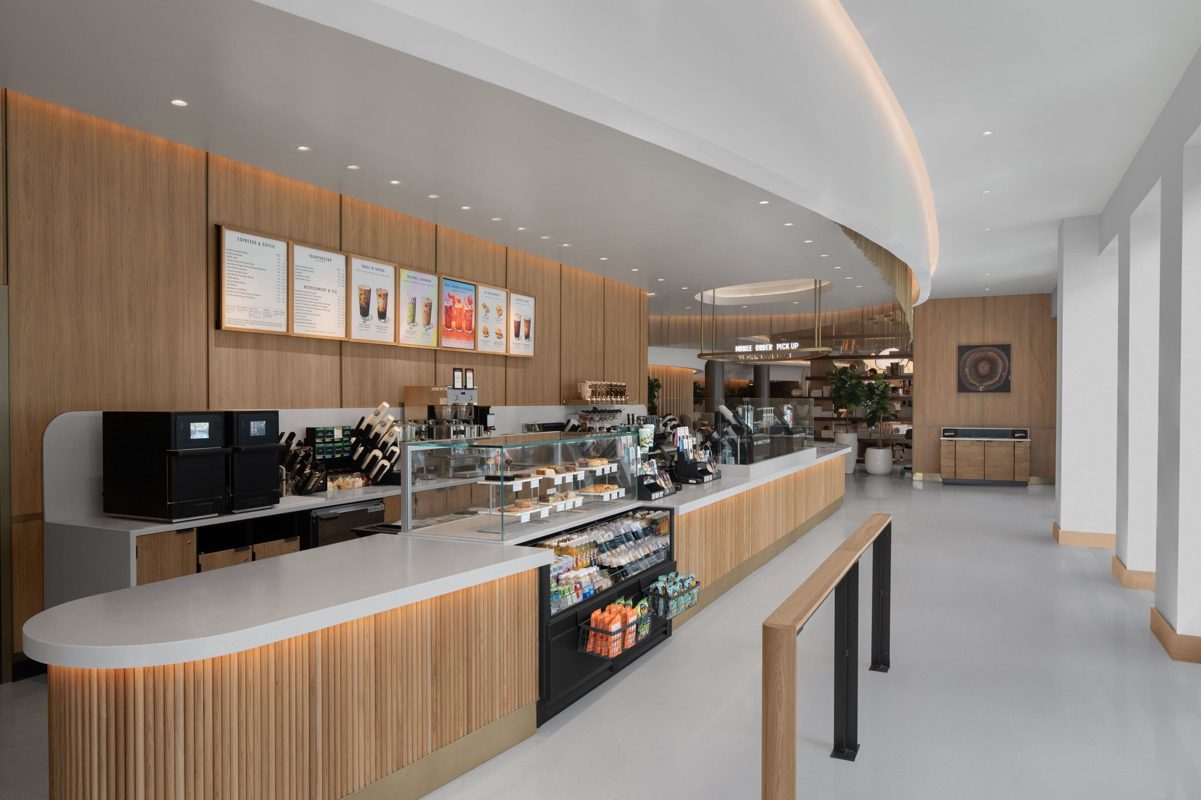 A modern cafe with a wooden counter, menu boards, and a coffee machine.