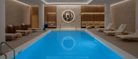 Uma área interna de piscina moderna com espreguiçadeiras e um espelho circular central.