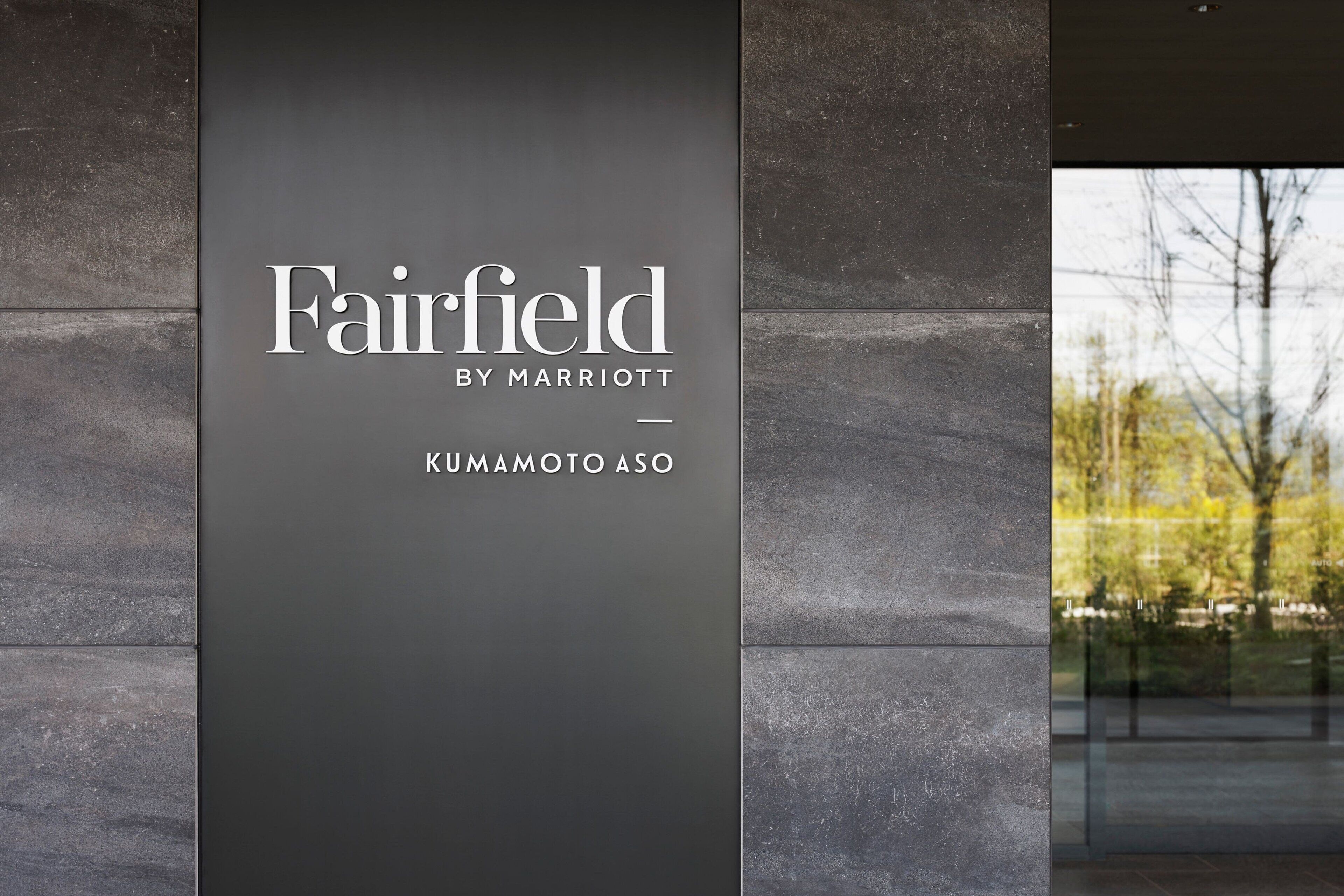 A sign for Fairfield by Marriott in Kumamoto Asō, featuring a modern design with a dark background and white text.