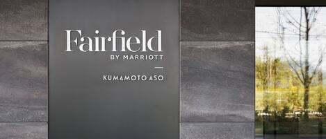 A sign for Fairfield by Marriott in Kumamoto Asō, featuring a modern design with a dark background and white text.