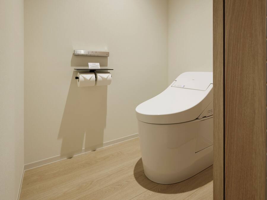Un baño moderno con inodoro, dispensador de toallas de papel y mecanismo para tirar de la cisterna.