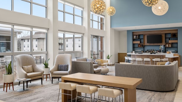 Un salón amplio con ventanas grandes, una barra y muebles modernos.