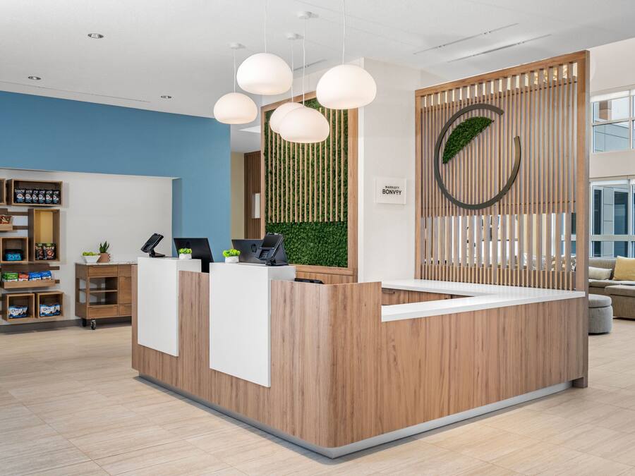 A reception desk with a wooden finish, a green vertical garden, and a circular logo on the wall.