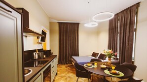 A compact kitchen with modern appliances, a dining area with a table and chairs, and a large window with curtains. - GuestHost - Chiara Comfy Apartment D (Udine)