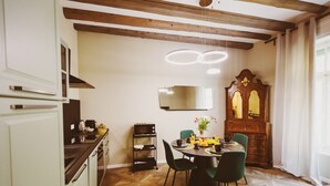 A kitchen with a wooden ceiling, a dining table with chairs, a microwave, and a cabinet.