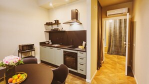 Una cocina compacta con electrodomésticos modernos, un área de comedor con mesa y sillas, y un pasillo que conduce a una habitación con cortina.
