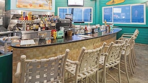 A bar area with a counter, chairs, and various bottles.