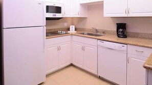 Efficient kitchen with white cabinetry, sink, and coffee maker.