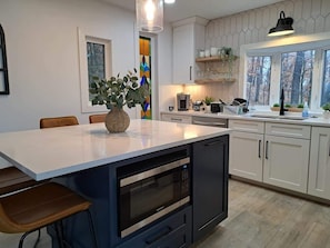 Una cocina moderna con una isla central, horno integrado y armarios blancos.