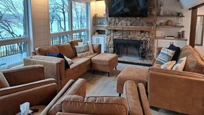 A cozy living room with a stone fireplace, leather sofas, and a flat-screen TV. - Island View McDonald Lake (Dent)