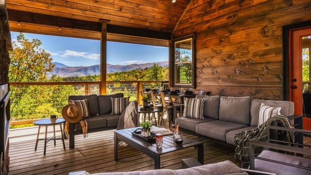 Une cabane en bois dotée d’une terrasse, aménagée avec des canapés, une table basse et un coin repas.