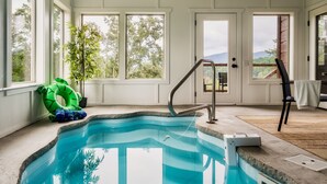 Une piscine intérieure avec de grandes fenêtres, une échelle et une chaise.