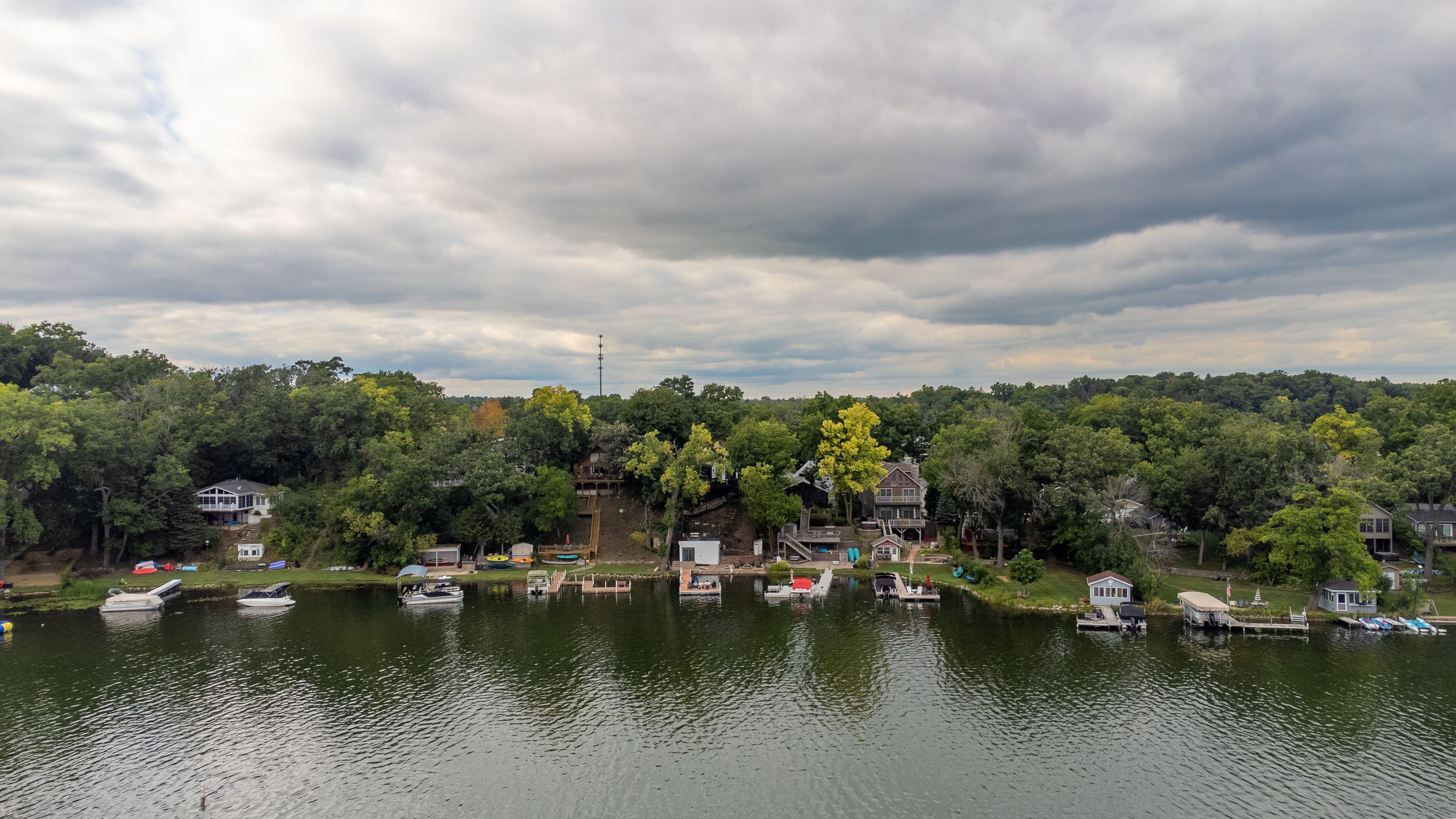 Une vue sur le lac, avec des bateaux amarrés, un quai et des maisons entourées d’arbres.
