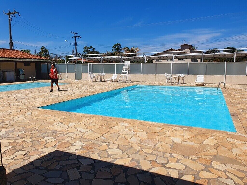 A swimming pool with stone tiles, a ladder, and lounge chairs.