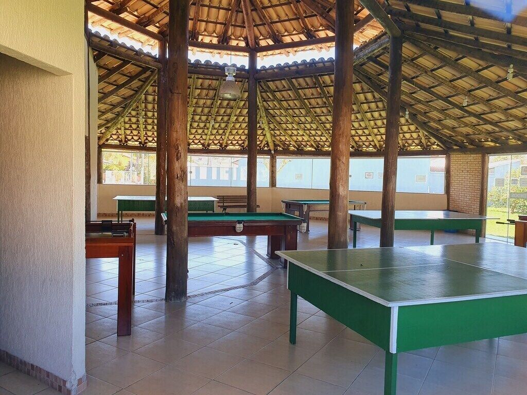 An indoor recreational area with multiple green ping pong tables, a pool table, and a billiards table.
