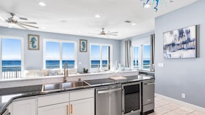 Een moderne keuken met een groot schiereiland, een vaatwasser en uitzicht op de oceaan.