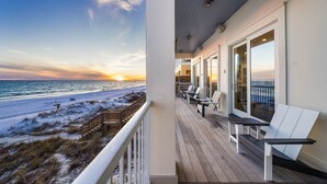 Un balcon avec vue sur la plage et l’océan au coucher du soleil.