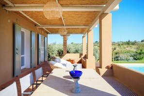 A covered outdoor area with a pool, a table with a blue bowl, and a chair. - Baglio di Verre (Menfi)