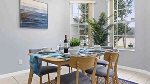 Uma sala de jantar com uma mesa posta para quatro pessoas, uma garrafa de vinho e um quadro na parede.