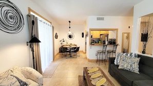 A modern living room with a sofa, a coffee table, and a dining area with a table and chairs. - Clearwater Condo w/Pool Access, 4Mi to Beach! (Clearwater)