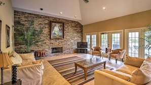 A spacious living room with a stone fireplace, comfortable seating, and large windows. - Clearwater Condo w/Pool Access, 4Mi to Beach! (Clearwater)