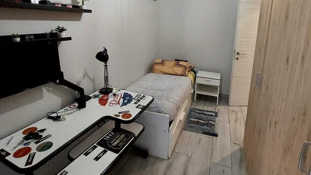 A compact bedroom with a bed, a desk with a chair, a wardrobe, and a world map on the wall. - Roman Holidays (Roma)