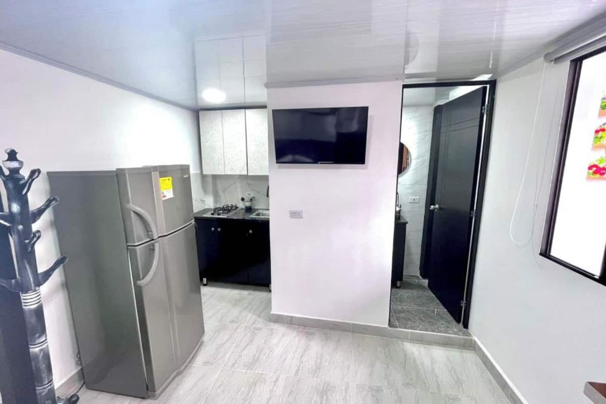 A compact kitchen with a refrigerator, stove, and microwave.