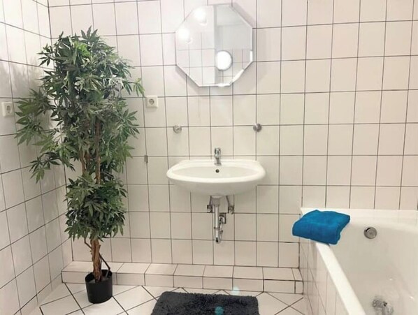 Une salle de bain avec un lavabo, un miroir et une baignoire.