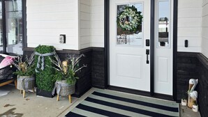 A front door with a wreath, a black mailbox, and potted plants. - Posh Pelican House is guest favorite in quaint resort town of Breezy Point! (Breezy Point)