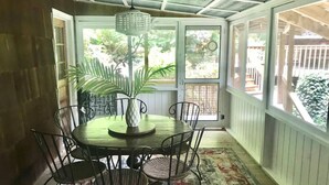 A covered patio with a round table and chairs, a hanging light fixture, and a view of the outdoors. - Fun on the River - Swim, Fish, Hike Near Tubing (Blue Ridge)