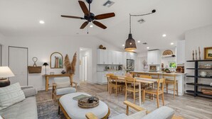 A spacious living room with a sofa, coffee table, and dining area. - Luxe Golden Hour - Private Pool & Pickleball Court, Outdoor Kitchen (Palm Beach Gardens)