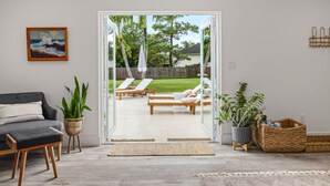 A living room with a sofa, a coffee table, and a potted plant. - Luxe Golden Hour - Private Pool & Pickleball Court, Outdoor Kitchen (Palm Beach Gardens)