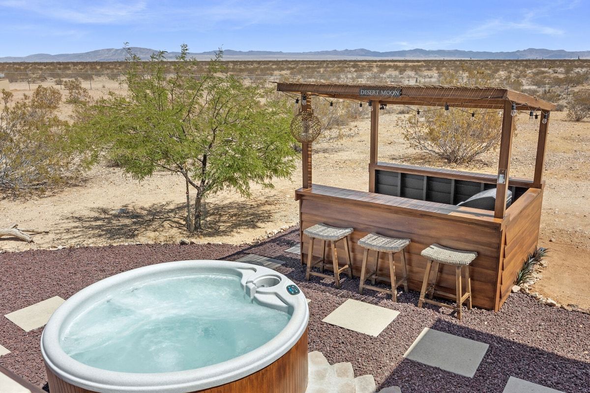 A hot tub with a wooden bar and seating area, surrounded by a desert landscape.