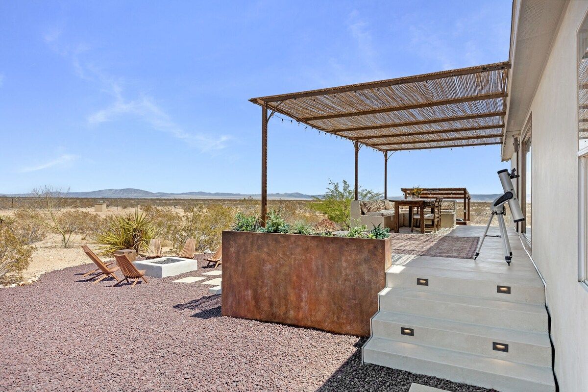 A covered outdoor seating area with a telescope, a dining table, and chairs.