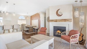 A spacious living room with a fireplace, comfortable seating, and a dining area. - Desert Moon-Hot Tub & Views Near Joshua Tree! (Joshua Tree)