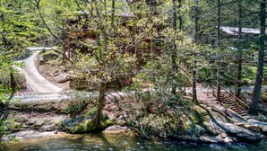 A forested area with a winding path leading to a bridge over a stream. - Toccoa River Fun + Hot Tub, Game Rm, Fish, Swim (Blue Ridge)