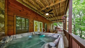 A hot tub area with a wooden deck and stone walls. - Toccoa River Fun + Hot Tub, Game Rm, Fish, Swim (Blue Ridge)