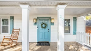 A porch with a blue door, white columns, and a wooden rocking chair.