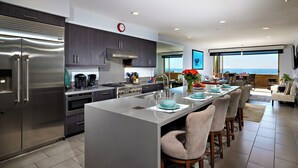 A modern kitchen with a central island, stainless steel appliances, and a large window overlooking the ocean. - Steps to the Sand | Modern Oceanfront Condo, A/C, Dog-Friendly, Walk to Pier (Oceanside)