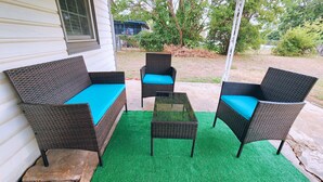 An outdoor patio with wicker furniture and a glass table.
