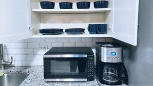 A kitchen with a microwave, coffee maker, and shelves with blue bowls and plates.