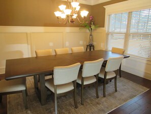 A conference room with a large table, six chairs, a vase with flowers, and a window with blinds. - Masters Housing -5.6 miles to Masters (Martinez)