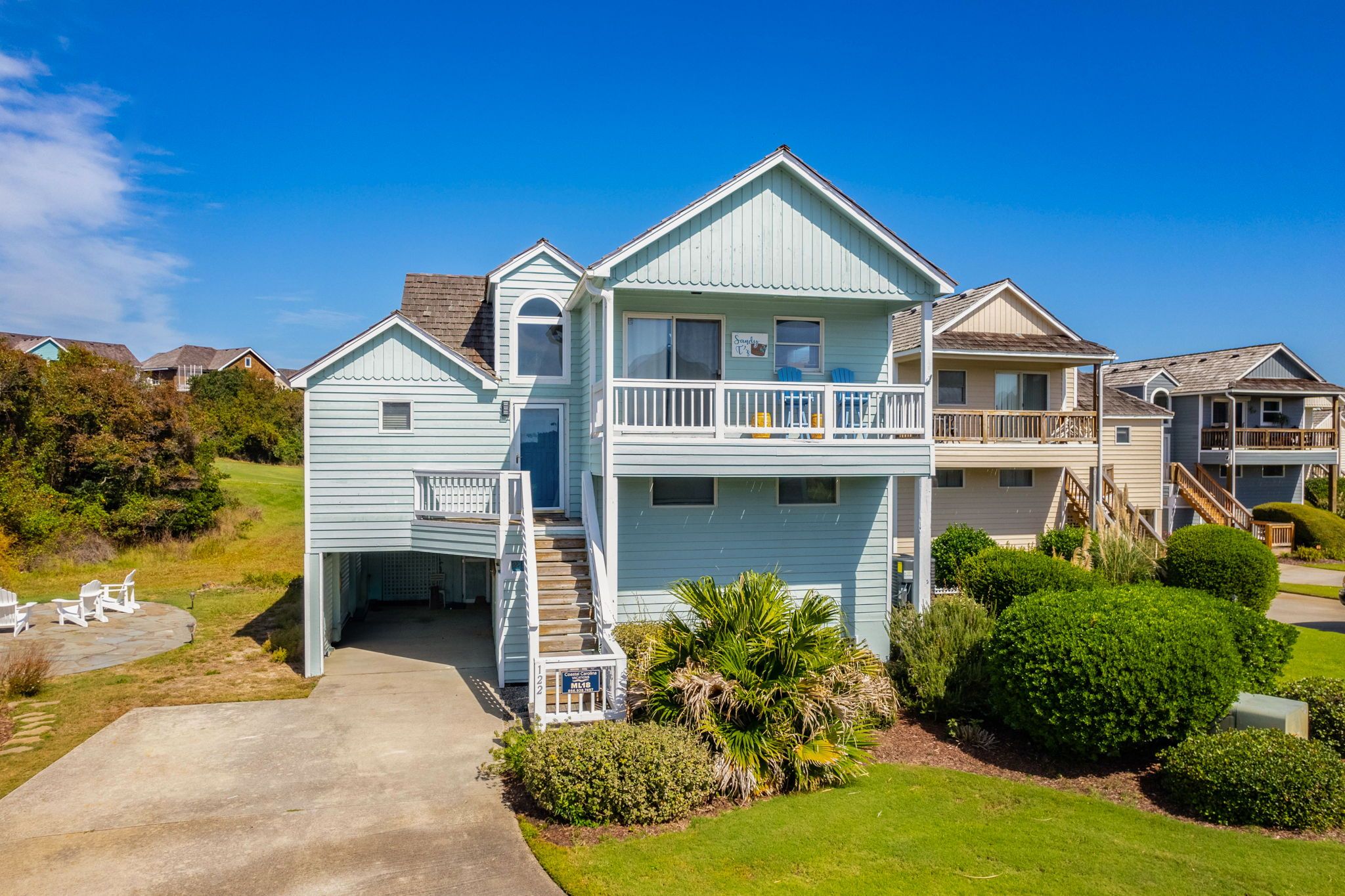 A two-story house with a front porch, a covered patio, and a small garden area.