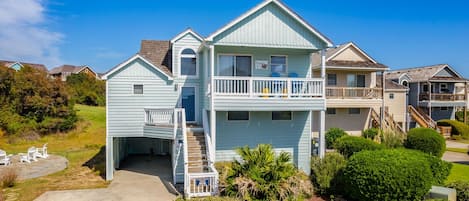 A two-story house with a front porch, a covered patio, and a small garden area.