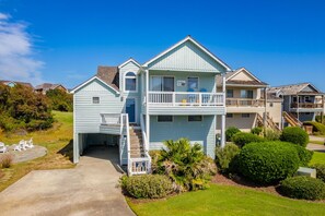 A two-story house with a front porch, a covered patio, and a small garden area.
