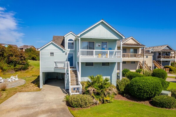 A two-story house with a front porch, a covered patio, and a small garden area.
