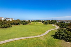 Ein Golfplatz mit einem gewundenen Weg, umgeben von Wohnhäusern und viel Grün.