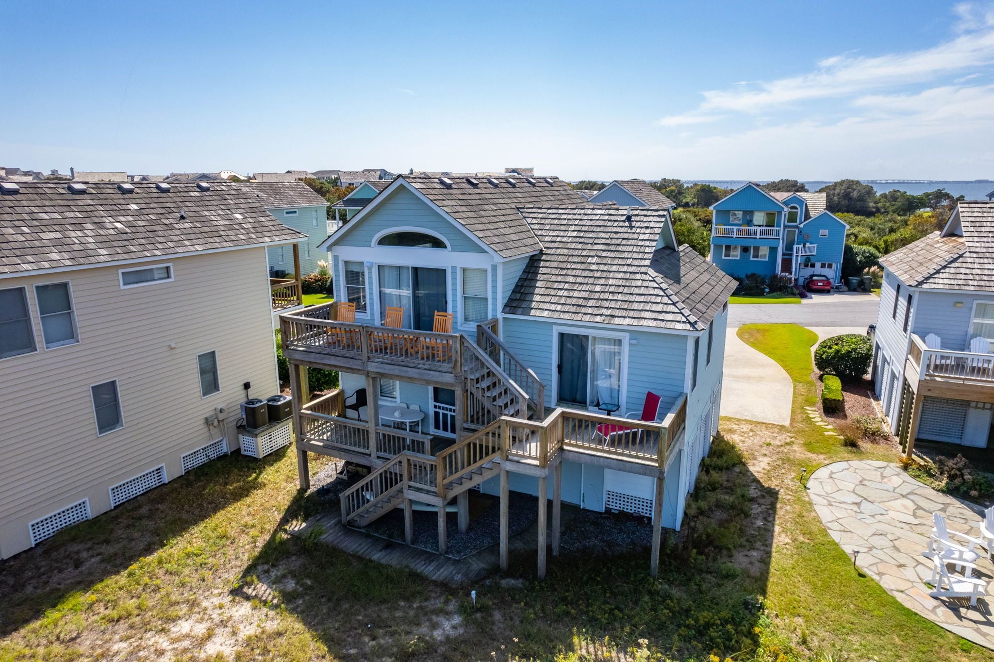 A two-story house with a balcony and a deck, surrounded by other similar houses.