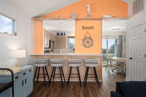 Una cocina con isla central, taburetes de bar y decoración de pared con temática náutica.